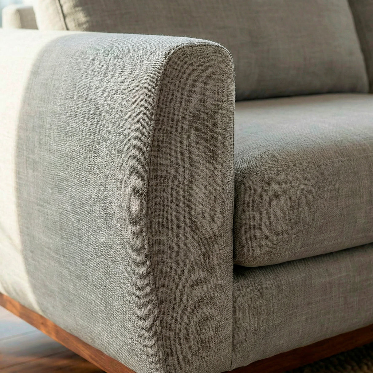 Acercamiento de reposabrazos sofá de tres cuerpos en tela lino color gris.