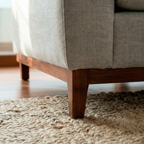 Acercamiento de pata de madera inmunizada de eucalipto brasileño de 
sofá de tres cuerpos en tela lino color gris.